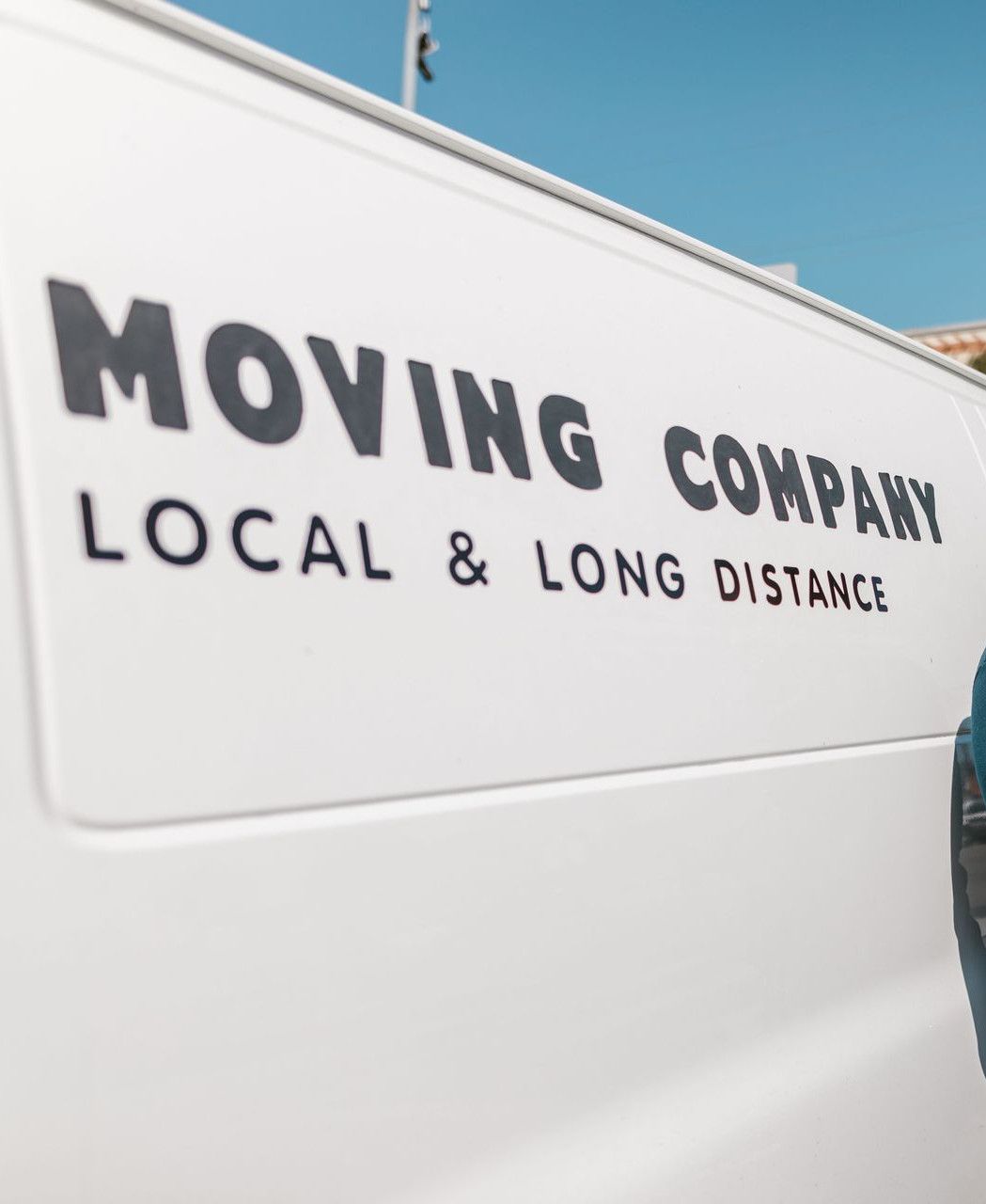 A cheerful mover standing confidently beside a moving company's van, ready for local or long distance relocation services.